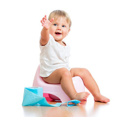 smiling baby sitting on chamber pot with toilet paper roll