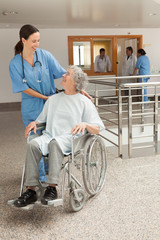 Wall Mural - Nurse smiling at old women sitting in wheelchair