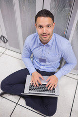 Poster - Smiling man using laptop in front of servers
