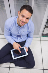 Poster - Smiling man using tablet pc beside servers