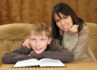 Beautiful happy Caucasian mother with her son reading a book