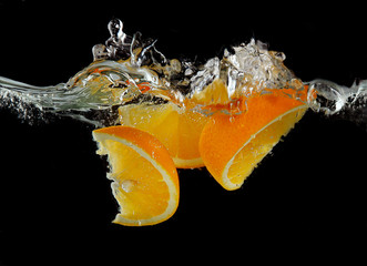 Canvas Print - Sliced orange in the water on black background