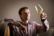 © lichtmeister - Pleased vintner looking at glass of white wine in cellar.