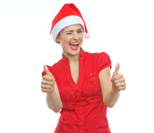 Happy Young Woman In Christmas Hat Winking And Showing Thumbs Up