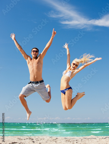 Tapeta ścienna na wymiar happy couple jumping on the beach