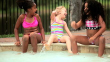 Multi ethnic children laughing and splashing in swimming pool