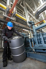 Oil Worker  in uniform dealing with silver oil barrel