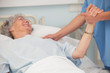 Elderly patient holding hand of nurse