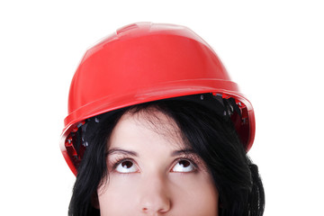 Confident female worker in helmet looking up