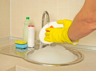 Men’s hands washing dish in the kitchen