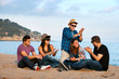 © karelnoppe - Group of friends singing on beach.