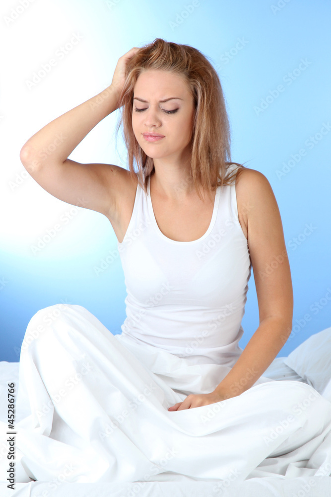 young beautiful woman in bed on blue background