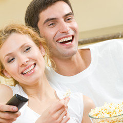 Wall Mural - Cheerful young couple watching TV together