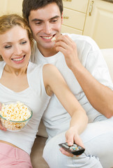 Wall Mural - Cheerful young couple watching TV together