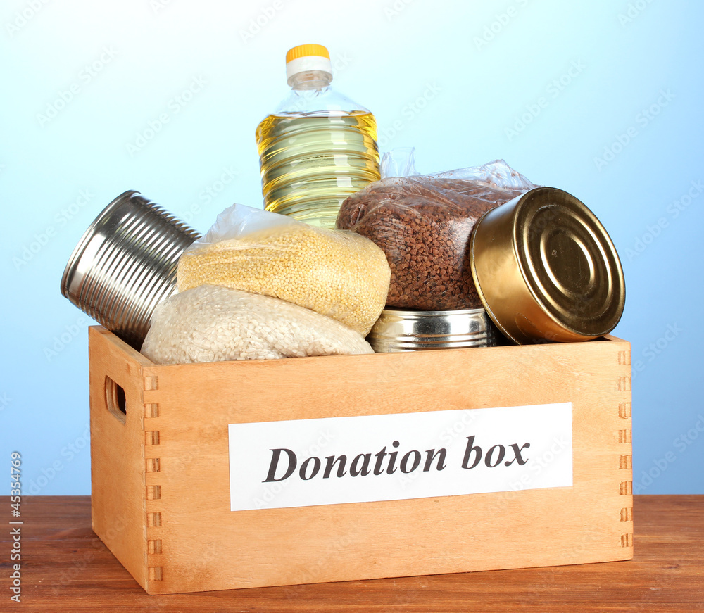 Donation box with food on blue background close-up