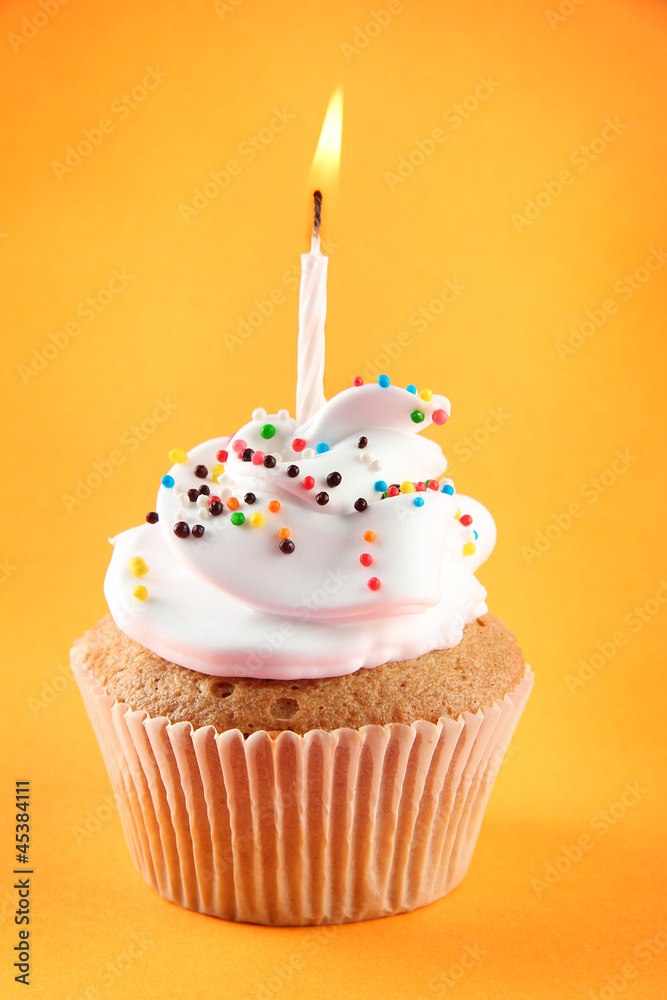 tasty birthday cupcake with candle, on orange background