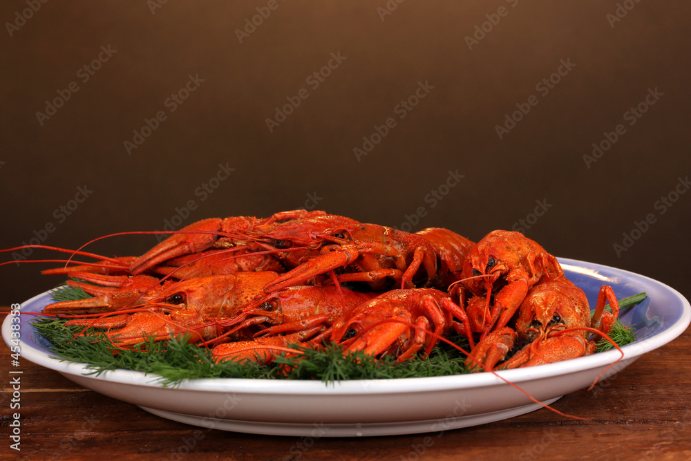 Tasty boiled crayfishes with fennel on table on brown