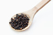 Black peppercorns in wooden spoon