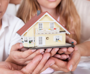 Family Sitting Holding Miniature Model Of House