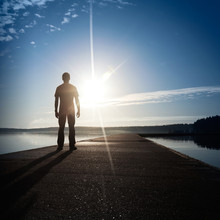 A Man Stands On The Concrete Pier Starring At The Setting Sun