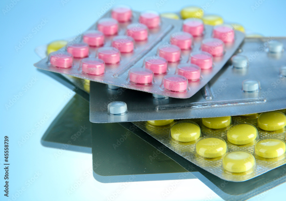 pills packed in blisters, on blue background