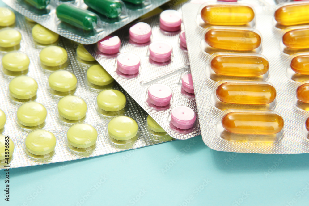 Capsules and pills packed in blisters, on blue background