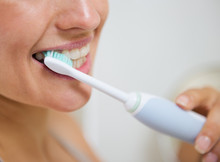 Closeup On Woman Brushing Teeth With Electric Toothbrush