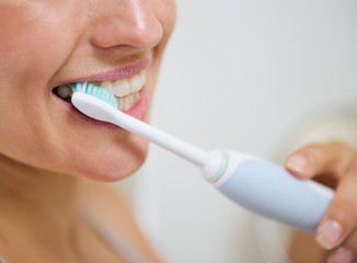 Poster - Closeup on woman brushing teeth with electric toothbrush