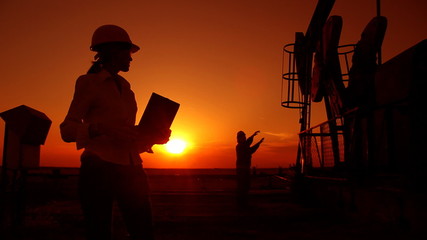 Canvas Print - Oil pump jack and oil workers at sunset