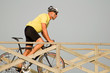 Mature man riding a bicycle over a wooden bridge