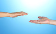 Women's hand goes to the man's hand on blue background