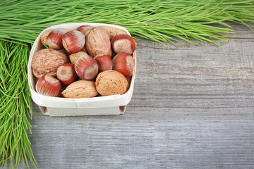 Christmas basket with wood, walnuts and almonds. On a wooden tex