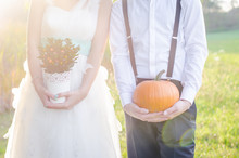 Bride And Groom Holding Flowers And Pumkin