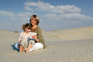 Wall Mural - mother and daughter play with tablet in desert