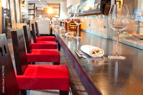 Naklejka dekoracyjna Red chairs near bar with glasses, towel in sushi restaurant