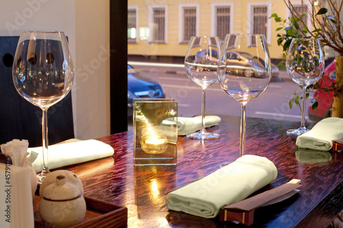 Obraz w ramie Table with glasses, candle, towels, sticks, with view on street