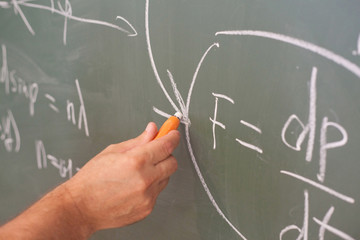 Scientist write formula on blackboard, focus on hand