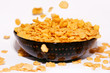 Golden cornflakes falling in a bowl isolated on white