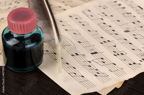 Obraz na PCV Musical notes and feather on wooden table
