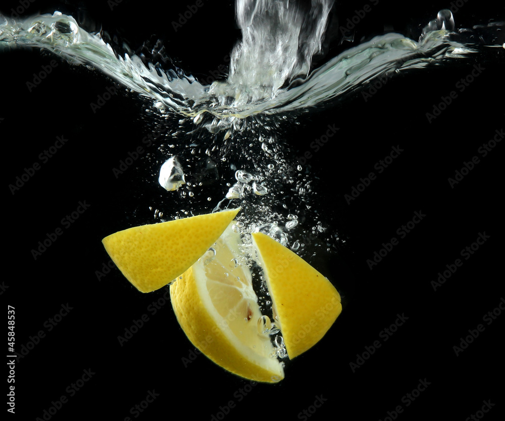 Sliced lemon in the water on black background