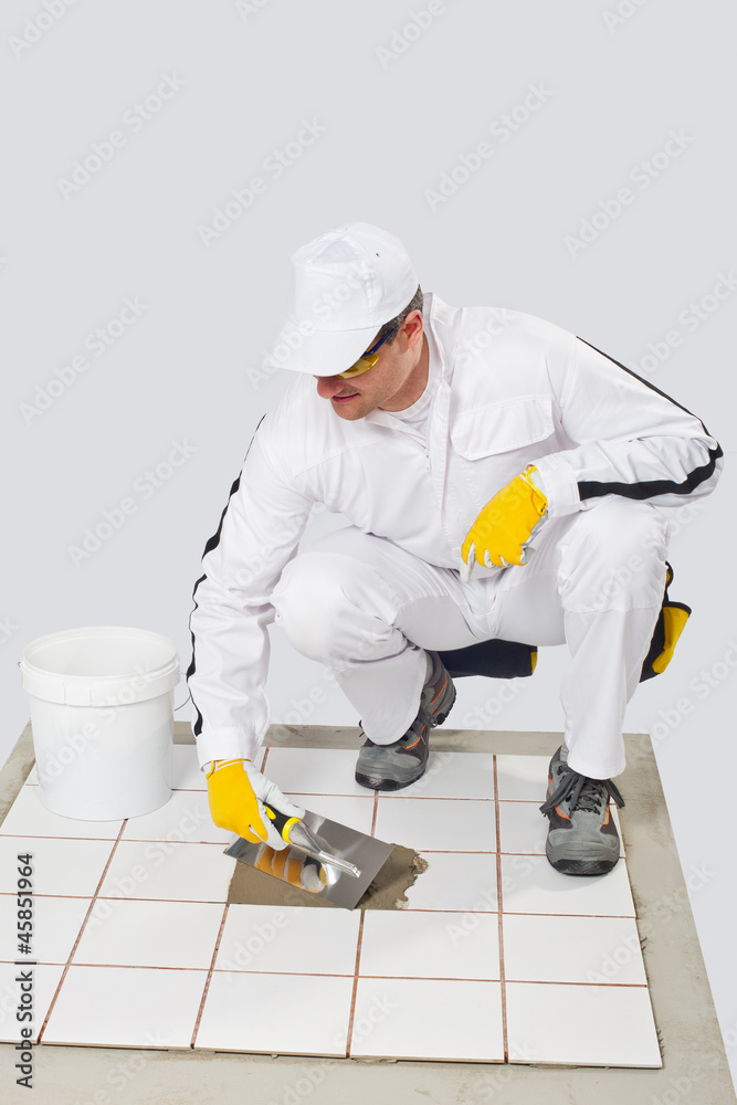 Worker repairs old white tiles with tile adhesive and trowel