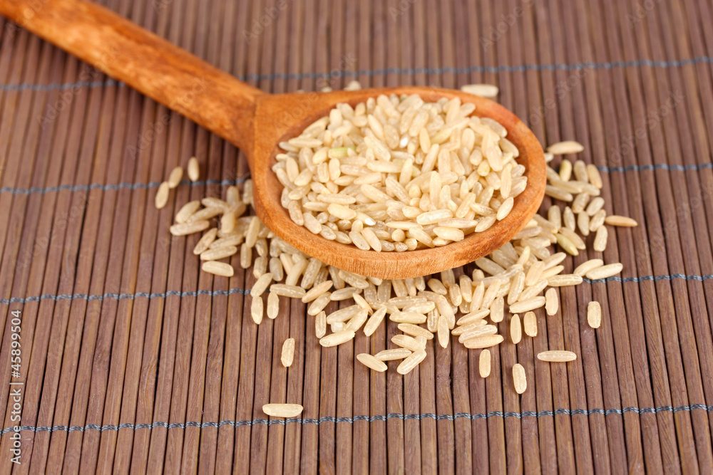 rice  in wooden  spoon on bamboo mat