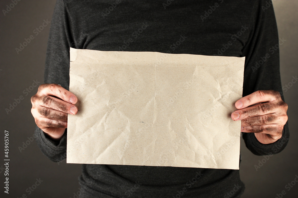 homeless man with cardboard, on black background close-up