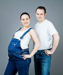 Happy pregnant couple over grey background.