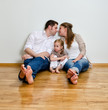 © M-Production - Happy family sitting on the floor against the wall