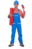 Fototapeta Las - Tradesman holding corrugated tubing and a pipe wrench