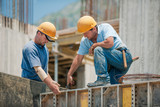 Fototapeta Krajobraz - Two construction workers installing concrete formwork frames