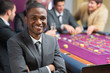 Smiling man sitting arms crossed at roulette table