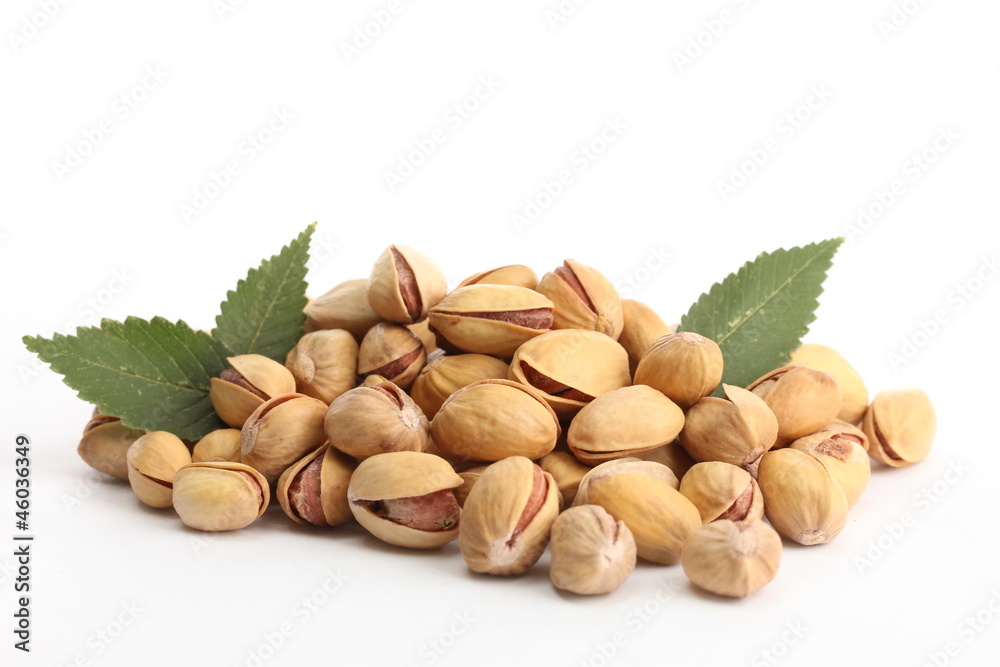 tasty pistachio nuts with leaves, isolated on white