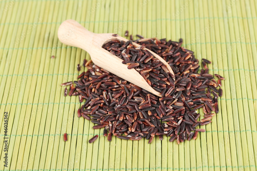 black rice  in wooden  scoop on bamboo mat